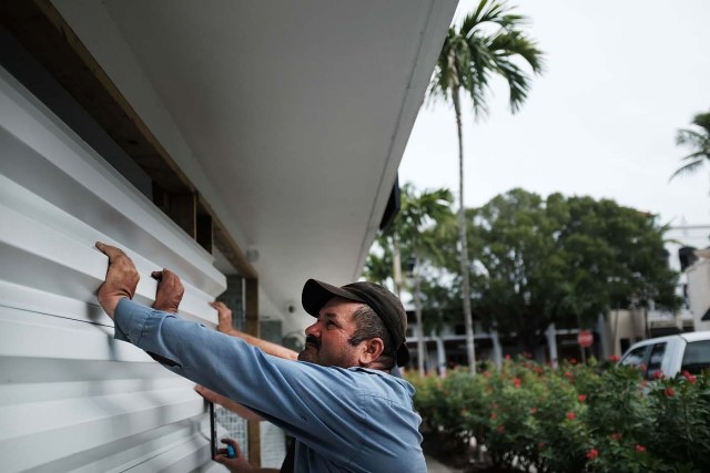 NAPLES, FL - SEPTEMBER 09: Men hold up metal siding as it is placed in front of a business in downtown Naples before the arrival of Hurricane Irma into Southwest Florida on September 9, 2017 in Naples, Florida. The Naples area could begin to feel hurricane-force winds from Irma by 11 a.m. Sunday and experience wind gusts over 100 mph from Sunday through Monday.   Spencer Platt/Getty Images/AFP