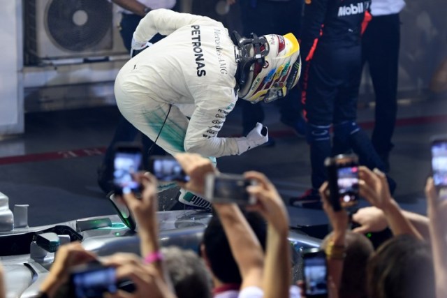 Mercedes' British driver Lewis Hamilton celebrates winning the Formula One Singapore Grand Prix in Singapore on September 17, 2017.  / AFP PHOTO / MANAN VATSYAYANA