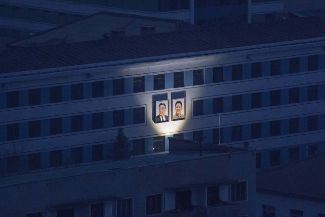 This photo taken on November 25, 2016 shows the illuminated portraits of late North Korean leaders Kim Il-Sung and Kim Jong-Il amid the night skyline of Pyongyang. North Korea suffers from perennial energy shortages, epitomised by satellite photos of the country at night, showing it as a largely dark quadrilateral between the bright lights of China and the South. / AFP PHOTO / Ed JONES / TO GO WITH NKorea-economy-electricity-politics,FOCUS by Sebastien BERGER