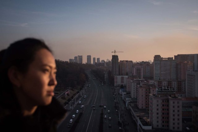 (FILES) In a file photo taken on November 29, 2016, a woman stands before the city skyline atop the Arch of Triumph in Pyongyang. North Korea suffers from perennial energy shortages, epitomised by satellite photos of the country at night, showing it as a largely dark quadrilateral between the bright lights of China and the South. / AFP PHOTO / ED JONES / TO GO WITH NKorea-economy-electricity-politics,FOCUS by Sebastien BERGER