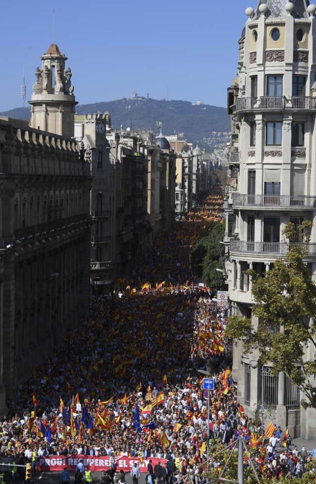 Protester hold a banner reading in Catalan "Enough, regain lucidity" during a demonstration called by "Societat Civil Catalans" (Catalan Civil Society) to support the unity of Spain on October 8, 2017 in Barcelona. Spain braced for more protests despite tentative signs that the sides may be seeking to defuse the crisis after Madrid offered a first apology to Catalans injured by police during their outlawed independence vote. / AFP PHOTO / LLUIS GENE