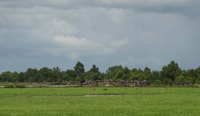 Rohingya refugees wait on the banks of the Naf river after crossing by boat from Myanmar into Bangladesh, at Whaikhyang on October 9, 2017. A top UN official said on October 7 Bangladesh's plan to build the world's biggest refugee camp for 800,000-plus Rohingya Muslims was dangerous because overcrowding could heighten the risks of deadly diseases spreading quickly. The arrival of more than half a million Rohingya refugees who have fled an army crackdown in Myanmar's troubled Rakhine state since August 25 has put an immense strain on already packed camps in Bangladesh. / AFP PHOTO / INDRANIL MUKHERJEE