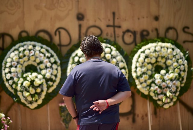 A man stands in front of a group of wreaths for the victims of Mexico's September 19 earthquake, during a tribute in their memory in front of a collapsed building at Tlalpan neighbourhood in Mexico City, on October 19, 2017. One month after the earthquake that jolted Mexico on September 19, flattening dozens of buildings across Mexico City and leaving 369 dead, many people are only just starting to pick up the pieces. / AFP PHOTO / RONALDO SCHEMIDT