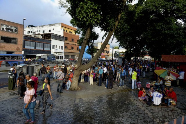 People queue at a bus stop in Catia, a neighbourhood of Caracas, on November 1, 2017. People queue for upto four hours to take a bus home in Venezuela, where mobilizing by land or plane has become a headache. / AFP PHOTO / Federico PARRA