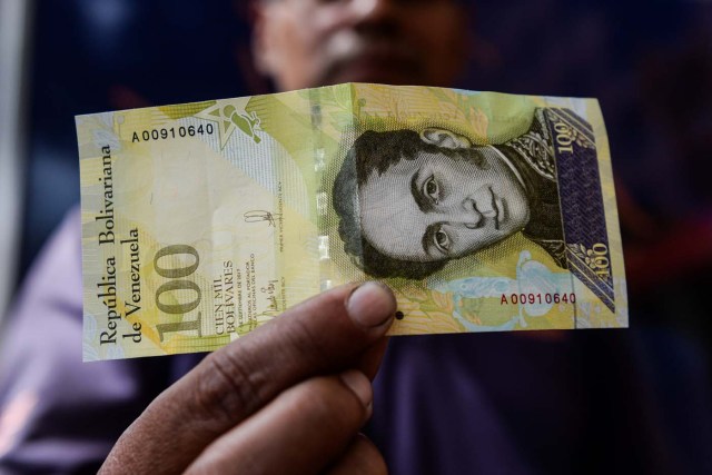 A man shows a new one hundred thousand-Bolivar-note in Caracas on November 9, 2017. The new bill is worth 29,89 US dollars in the official market and 2 dollars in the black market at November 9, 2017 exchange rate. / AFP PHOTO / FEDERICO PARRA