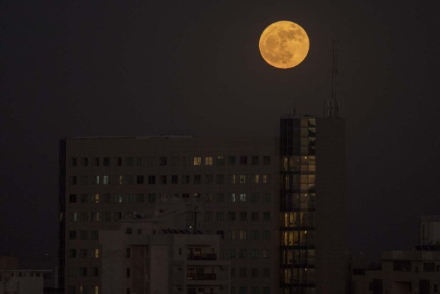 The 'supermoon' rises over a building in the Israeli city of Netanya, on December 3, 2017. The lunar phenomenon occurs when a full moon is at its closest point to earth. / AFP PHOTO / JACK GUEZ