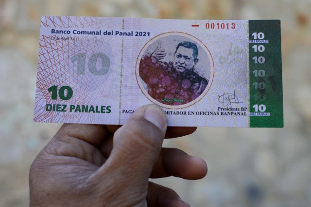 A man shows the new local community currency, the panal, launched in the "23 de Enero" working-class neighbourhood in Caracas on December 15, 2017. A collective in a hilltop shantytown in Caracas created its own currency, the panal, in an attempt to fight chronic shortages of cash in inflation-ridden Venezuela. The currency can be exchanged locally for staples like sugar, rice (produced in the neighborhood itself), and bread. / AFP PHOTO / FEDERICO PARRA