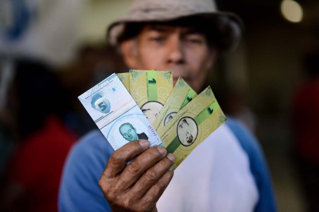 A man shows the new local community currency, the panal, launched in the "23 de Enero" working-class neighbourhood in Caracas on December 15, 2017. A collective in a hilltop shantytown in Caracas created its own currency, the panal, in an attempt to fight chronic shortages of cash in inflation-ridden Venezuela. The currency can be exchanged locally for staples like sugar, rice (produced in the neighborhood itself), and bread. / AFP PHOTO / FEDERICO PARRA