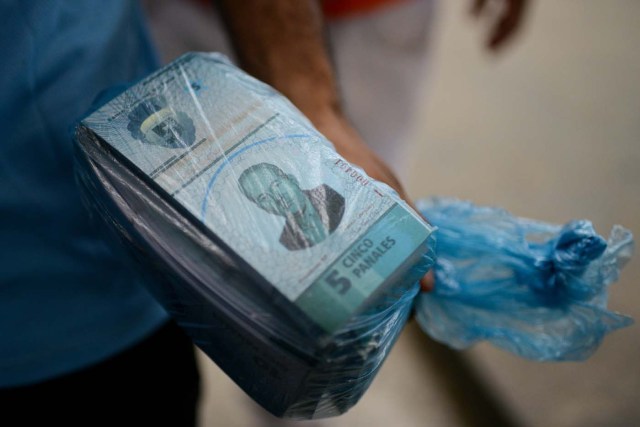 A man holds a pile of notes of the new local community currency, the panal, launched in the "23 de Enero" working-class neighbourhood in Caracas on December 15, 2017. A collective in a hilltop shantytown in Caracas created its own currency, the panal, in an attempt to fight chronic shortages of cash in inflation-ridden Venezuela. The currency can be exchanged locally for staples like sugar, rice (produced in the neighborhood itself), and bread. / AFP PHOTO / FEDERICO PARRA