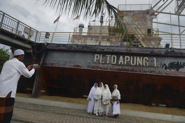 Acehnese pose for a photo next to a ship-turned-into a memorial which was pushed some 2.5 kilometres (1.55 miles) inland by the 2004 tsunami in Banda Aceh on December 26, 2017, as visitors remember one of the worst natural disasters in human history. Some 170,000 lives were lost in the country when a 9.1-magnitude "megathrust" quake struck Aceh, a predominantly Muslim province in the northern tip of Sumatra island, bringing about massive waves that also hit coastal areas as far away as Somalia and killing 50,000 others in various countries. / AFP PHOTO / CHAIDEER MAHYUDDIN