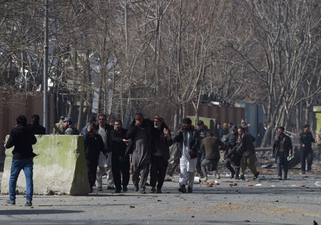 Afghan volunteers and policemen help wounded at the scene of a car bomb exploded in front of the old Interior Ministry building in Kabul on January 27, 2018. An ambulance packed with explosives blew up in a crowded area of Kabul on January 27, killing at least 17 people and wounding 110 others, officials said, in an attack claimed by the Taliban. / AFP PHOTO / WAKIL KOHSAR