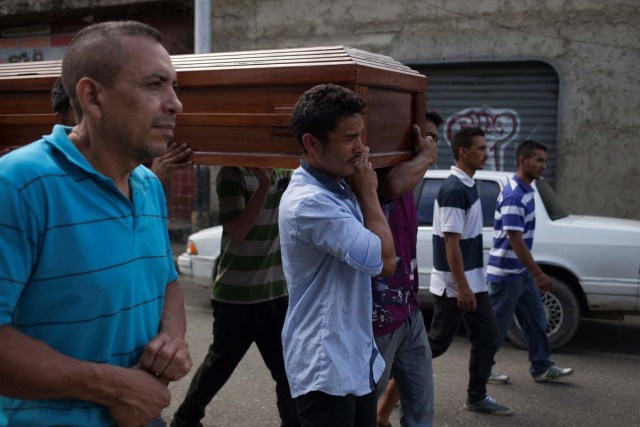 Bernabe Moya carries the coffin of his wife Alexandra Conopoy, a pregnant 18 year-old killed during an incident over scarce of pork, according to local media, in Charallave, Venezuela January 1, 2018. Picture taken January 1, 2018. REUTERS/Adriana Loureiro