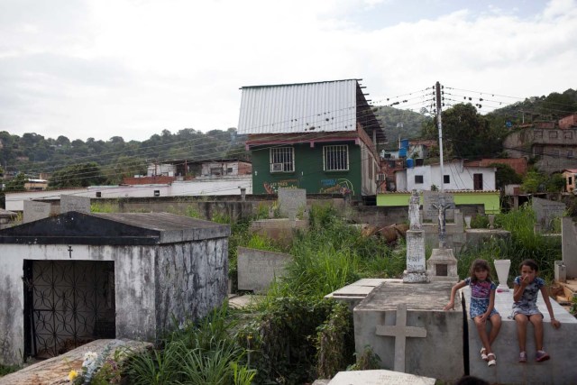 Girls sit on a tomb during the burial ceremony of Alexandra Conopoy, a pregnant 18 year-old killed during an incident over scarce of pork, according to local media, in Charallave, Venezuela January 1, 2018. Picture taken January 1, 2018. REUTERS/Adriana Loureiro