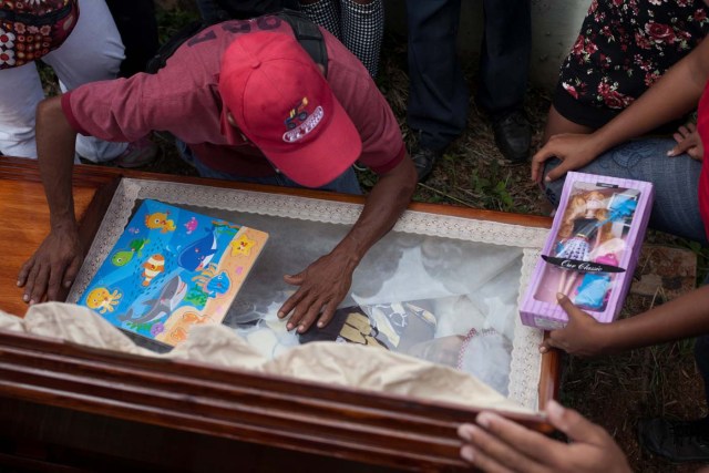 Alexander Conopoy reacts over the coffin of his daughter Alexandra Conopoy, a pregnant 18 year-old killed during an incident over scarce of pork, according to local media, in Charallave, Venezuela January 1, 2018. Picture taken January 1, 2018. REUTERS/Adriana Loureiro