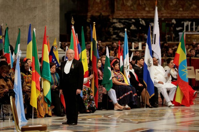 A Vatican gentleman stands in front of migrants holding their countries' flags as they wait for the arrival of Pope Francis to lead a special mass to mark International Migrants Day in Saint Peter's Basilica at the Vatican January 14, 2018. REUTERS/Max Rossi