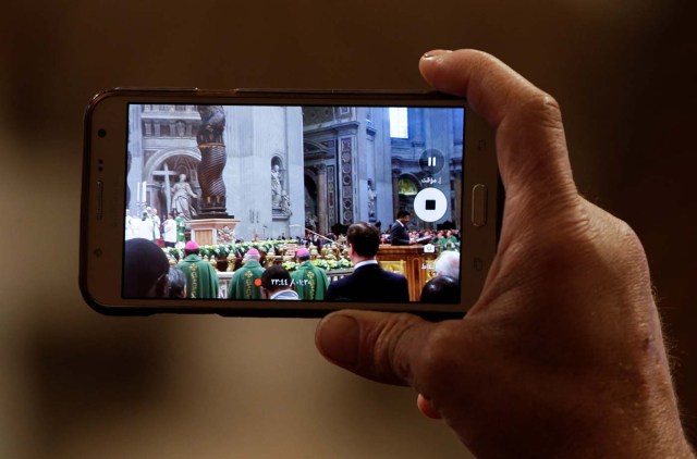 A migrant takes pictures as Pope Francis leads a special mass to mark International Migrants Day in Saint Peter's Basilica at the Vatican January 14, 2018. REUTERS/Max Rossi