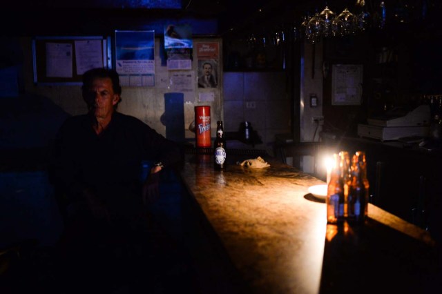 An employee remains at a liquor store during a partial power cut in Caracas on February 6, 2018. / AFP PHOTO / FEDERICO PARRA