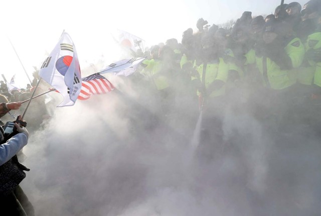 Police try to extinguish burnt portraits of North Korean leader Kim Jong Un during an anti-North Korea protest before the opening ceremony for the Pyeongchang 2018 Winter Olympics in Pyeongchang, South Korea, February 9, 2018. REUTERS/Edgar Su