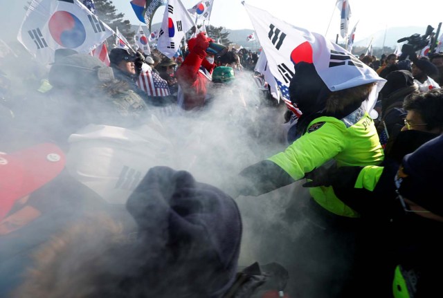 Police (in green) stop demonstartors from burning portraits of North Korean leader Kim Jong Un during an anti-North Korea protest before the opening ceremony for the Pyeongchang 2018 Winter Olympics in Pyeongchang, South Korea, February 9, 2018. REUTERS/Edgar Su