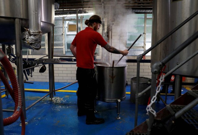 Un trabajador extrae líquido de una maceración y salta en la cervecería Windsor and Eton en Windsor, Gran Bretaña, el 11 de abril de 2018. Fotografía tomada el 11 de abril de 2018. REUTERS / Peter Nicholls