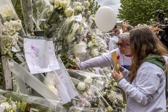 Angelique's sister (R) and mother (2ndR) lay flowers during a march in Wambrechies, northern France, on May 1, 2018, in tribute to Angelique, a 13-year-old girl who was killed and raped on April 25. The body of Angelique, who had disappeared since April 25, was found in the night from April 28 to April 29 in the countryside in Quesnoy-sur-Deule, northern France. David Ramault, 45 years old, who confessed the crime, was arrested in the night from April 30 to May 1 for kidnapping, rape and murder on minor under 15 years. / AFP PHOTO / Philippe HUGUEN