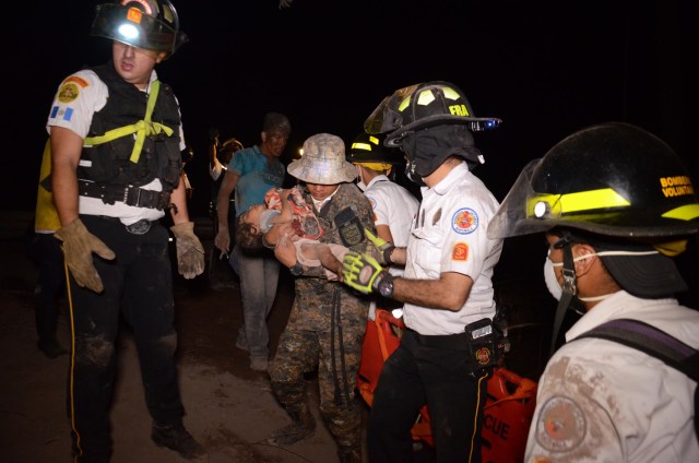 Un bombero voluntario carga a un niño después de la erupción del volcán Fuego, en el pueblo de El Rodeo, departamento de Escuintla, a 35 km al sur de Ciudad de Guatemala el 3 de junio de 2018. / AFP PHOTO / NOE PEREZ