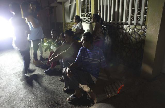 Los residentes se reúnen en una esquina cuando cae la noche en Maracaibo, Venezuela. El repelente de insectos es demasiado costoso, por lo que un residente quema una caja de cartón de huevos porque el fuego lento ayuda a mantener a los mosquitos alejados. / Foto AP