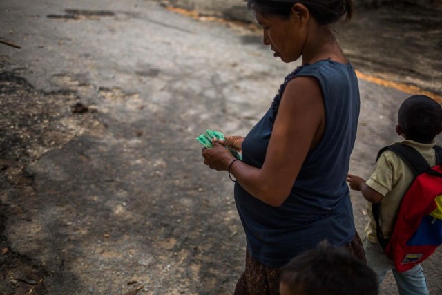 Fotografía fechada el 10 de mayo de 2018 que muestra a una mujer de la etnia Warao mientras cuenta dinero en efectivo, en Maturín (Venezuela). Unos 120 indígenas distribuidos en cerca de 30 palafitos de precaria elaboración conforman la comunidad de Morichal Largo, un asentamiento de la etnia Warao ubicado en el sur de Venezuela, que resiste debajo de un puente la miseria e insalubridad propia de la crisis nacional. EFE/Cristian Hernández