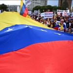 Los venezolanos que viven en España tienen una bandera gigante venezolana mientras protestan en apoyo de la oposición venezolana durante una manifestación en Madrid el 1 de mayo de 2019. -