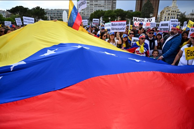 Los venezolanos que viven en España tienen una bandera gigante venezolana mientras protestan en apoyo de la oposición venezolana durante una manifestación en Madrid el 1 de mayo de 2019. - 